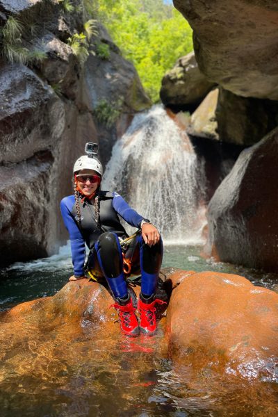 Woman smiling, sitting in front of small waterfall in Canyoning level 2 Ribeira do Cidrão, Madeira