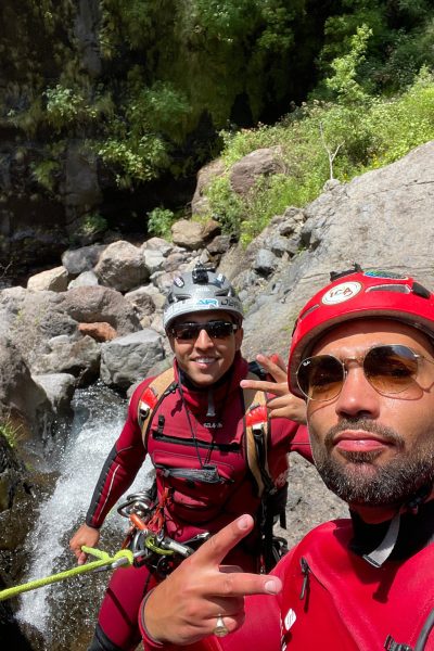José and Bruno, Go Explore Madeira team, smiling while hanging on a cliff wall.